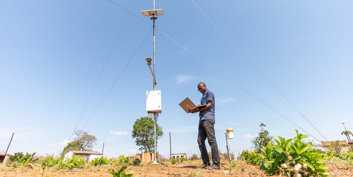 Man standing under weather station with laptop