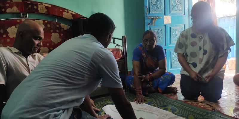 A man shows a map to a community member in their house in Mumbai.