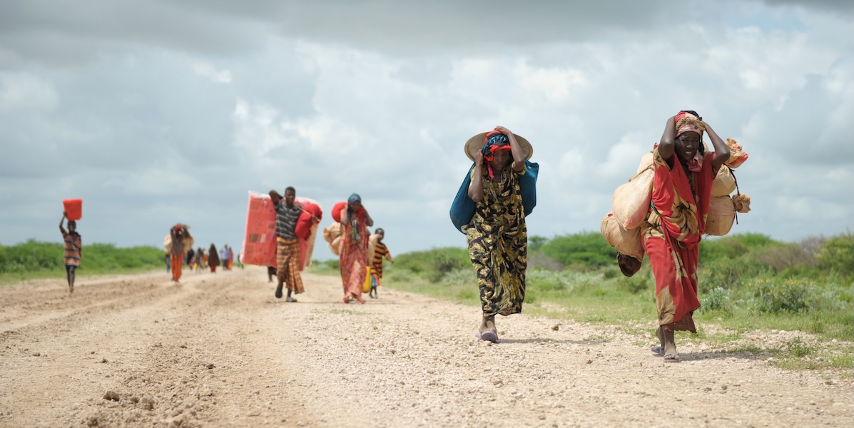 Somalian refugees walking down a street carrying their belongings 