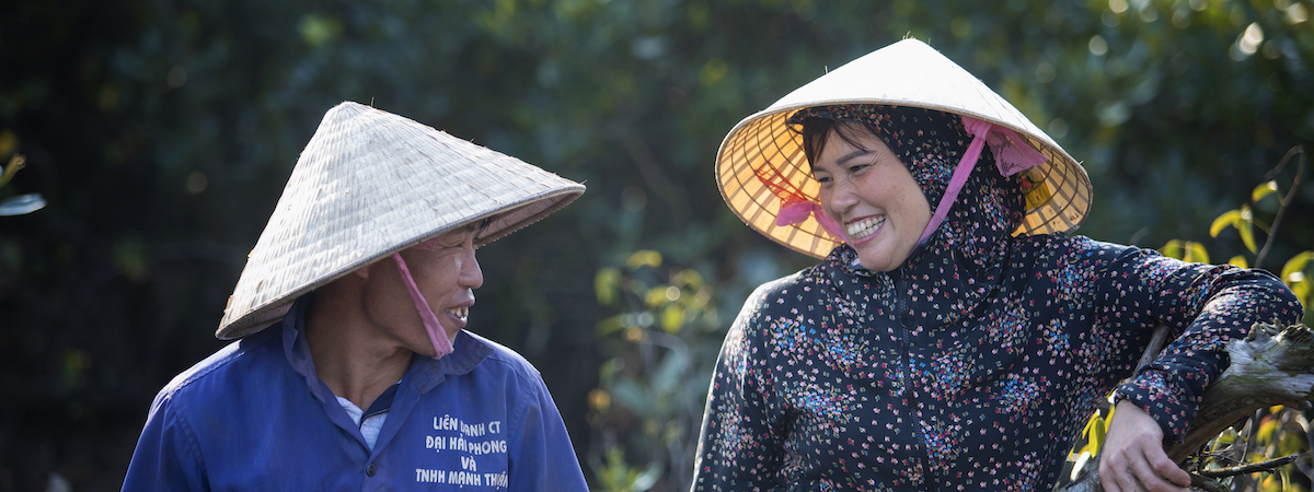 Two Vietnamese farmers looking at each other and smiling 