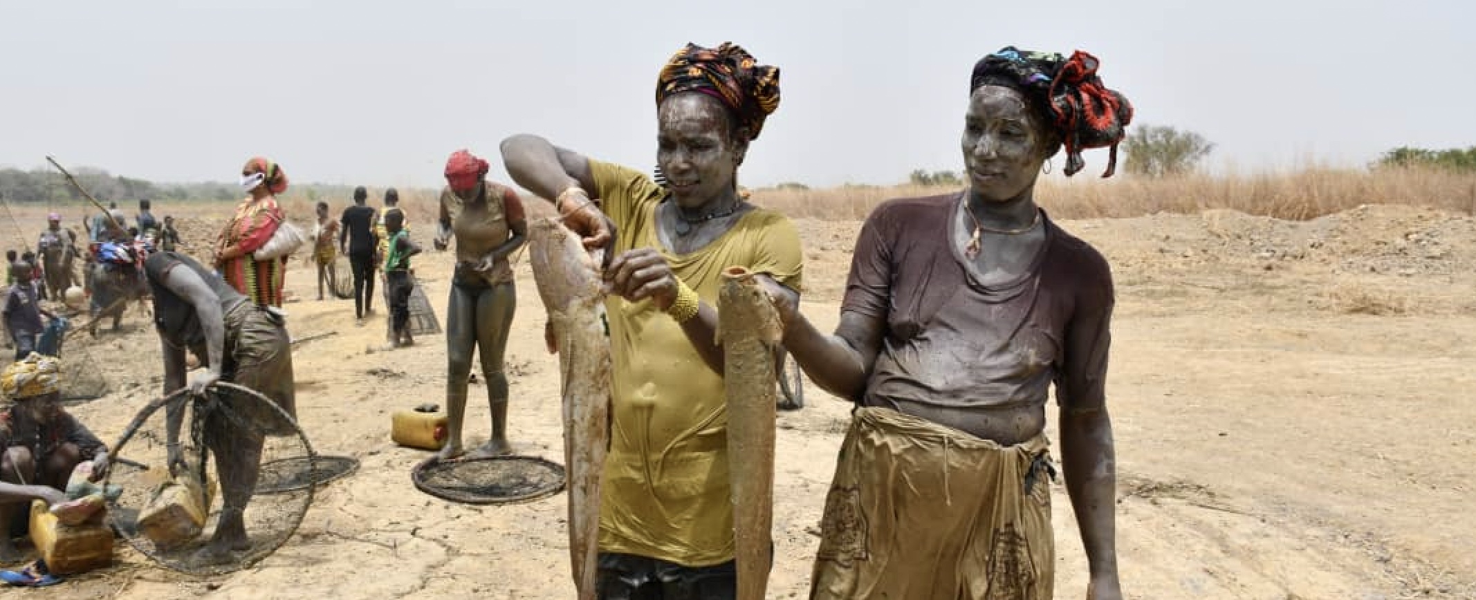 Two Guinean women holding fish 