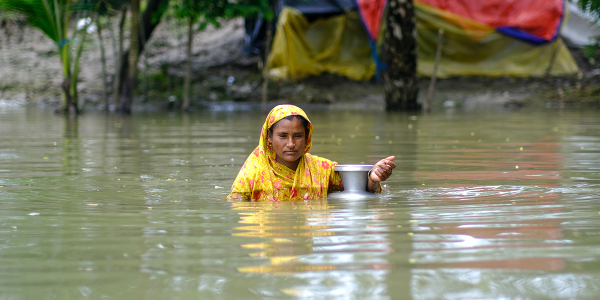 A woman wades through flood waters in coastal Bangladesh