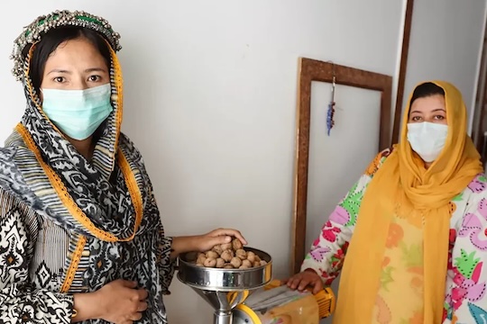 Sumaira-and-Fatima-at-their-shop-in-Khaplu-with-the-oil-extraction-machine-used-to-produce-rare-sea-buckthorn-oil,-known-for-itshealth-benefits